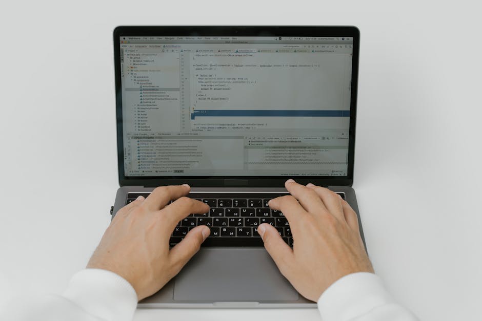 Close-up of hands coding on a laptop, showcasing software development in action